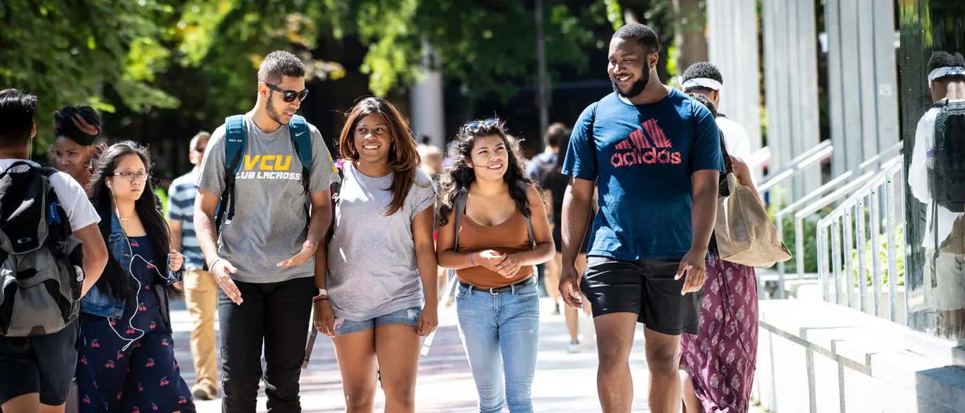 four v.c.u. students walking and laughing on a sunny day