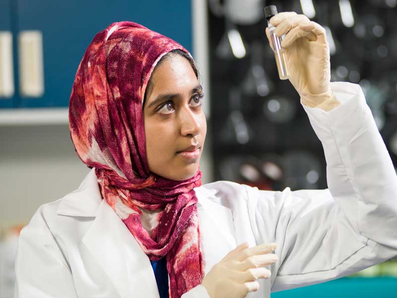 a student in a lab examining a substance in a test tube