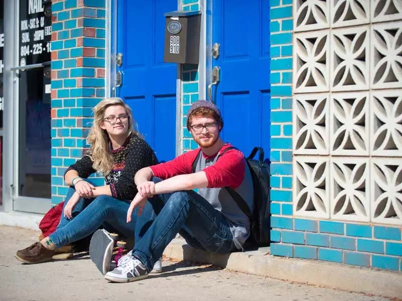 two v.c.u. students sit in a doorway taking a break from skateboarding