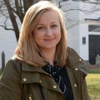 Woman in front of white historic home