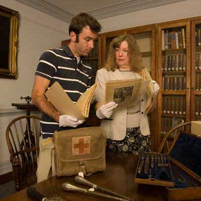 a professor and student studying historical materials and artifacts