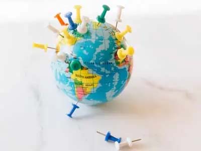 a miniature globe with push pins stuck in various points around it