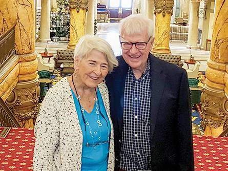 Laura and Harold Greer stand at the top of a carpeted staircase in the Jefferson Hotel
